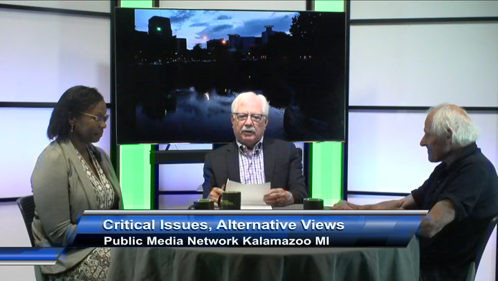 Three people seated at a table in a TV studio. A banner on the bottom of the picture reads ''Critical Issues, Alternative Views'' and ''Public Media Network Kalamazoo MI''